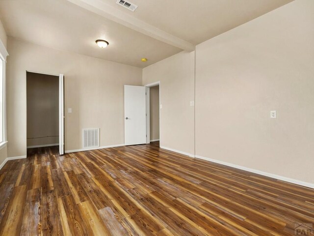 empty room featuring dark wood finished floors, visible vents, and baseboards