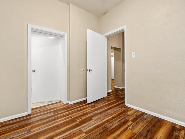 unfurnished bedroom with baseboards and dark wood finished floors