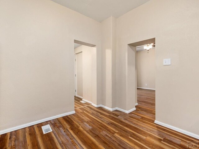 unfurnished room with baseboards, visible vents, and dark wood finished floors