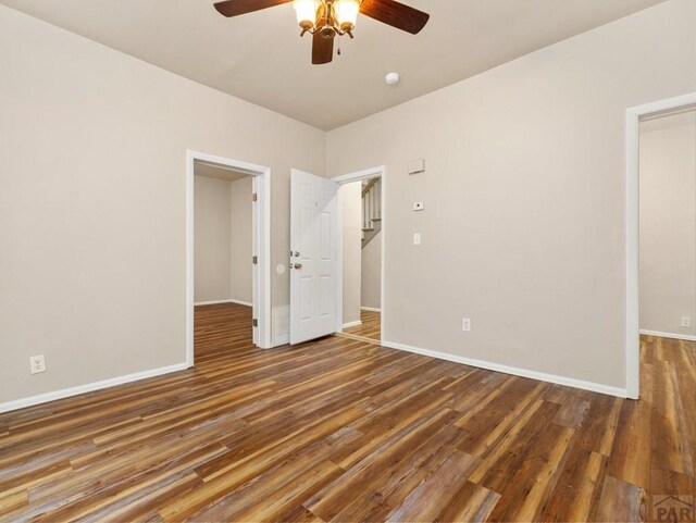 spare room with dark wood-style floors, baseboards, and a ceiling fan