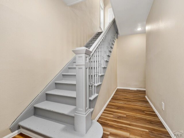 staircase with baseboards and wood finished floors