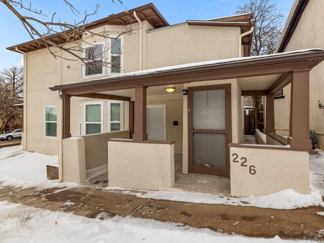 townhome / multi-family property featuring covered porch and stucco siding