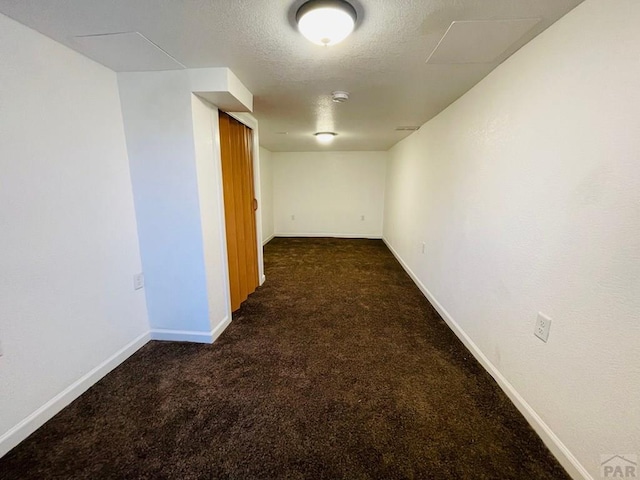 corridor with carpet floors, a textured ceiling, and baseboards