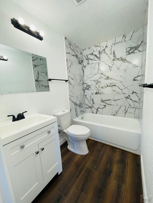 bathroom with a textured ceiling, toilet, wood finished floors, vanity, and bathing tub / shower combination