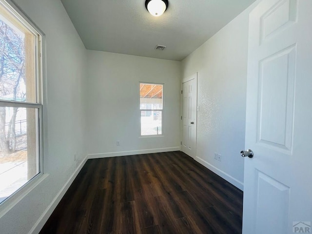 unfurnished room with a wealth of natural light, visible vents, and baseboards