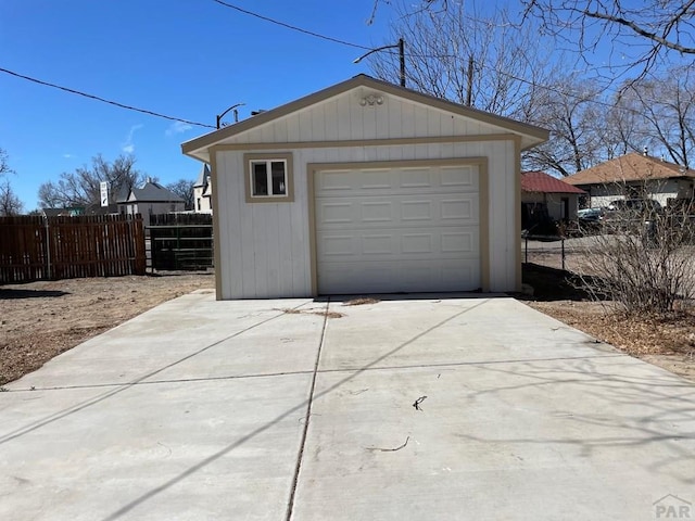 detached garage with concrete driveway and fence