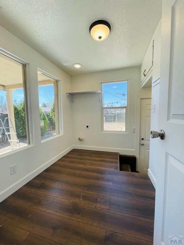 clothes washing area featuring cabinet space, baseboards, dark wood finished floors, a healthy amount of sunlight, and electric dryer hookup