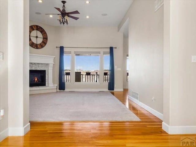 unfurnished living room featuring recessed lighting, a glass covered fireplace, ceiling fan, wood finished floors, and baseboards