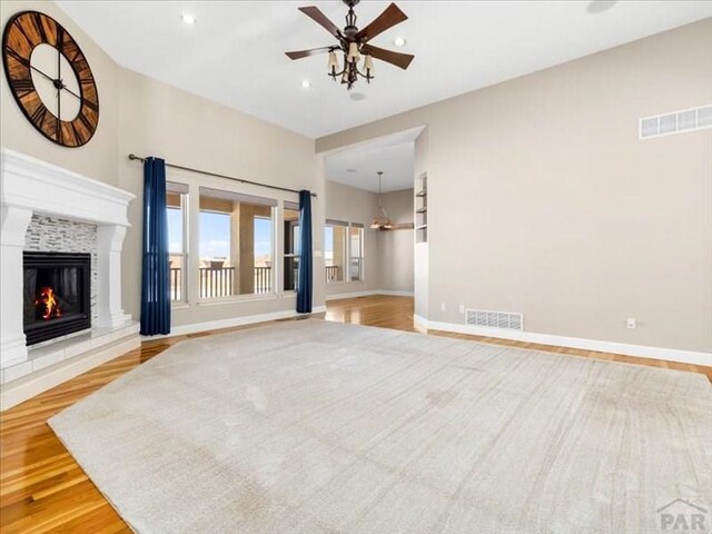 unfurnished living room featuring light wood-type flooring, baseboards, visible vents, and a glass covered fireplace