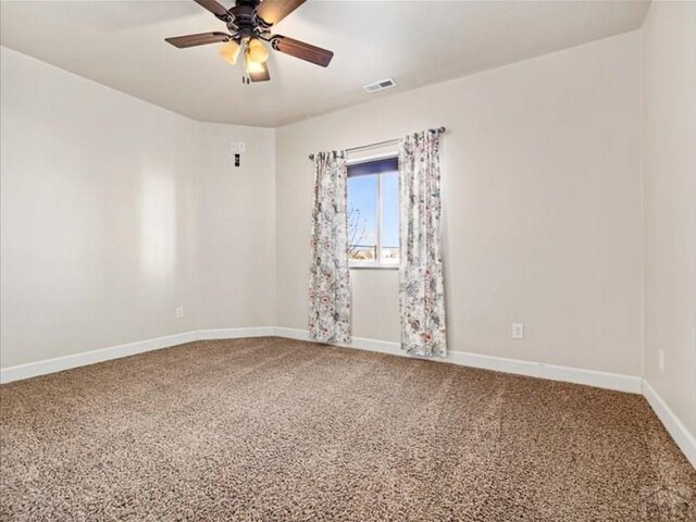 spare room with carpet floors, visible vents, baseboards, and a ceiling fan