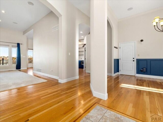 foyer entrance with baseboards, visible vents, arched walkways, and wood finished floors