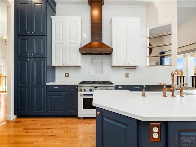 kitchen with blue cabinetry, custom range hood, high end range, and light countertops