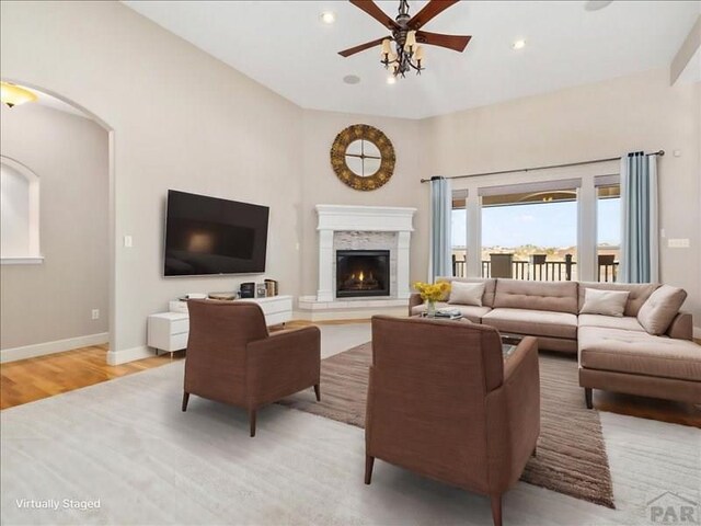 living area featuring recessed lighting, a ceiling fan, light wood-type flooring, a lit fireplace, and baseboards