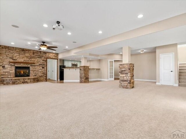 unfurnished living room featuring light carpet, ceiling fan, stairs, a stone fireplace, and recessed lighting