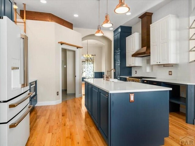 kitchen featuring light countertops, white refrigerator with ice dispenser, white cabinetry, and decorative light fixtures