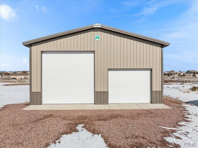 snow covered garage with a detached garage