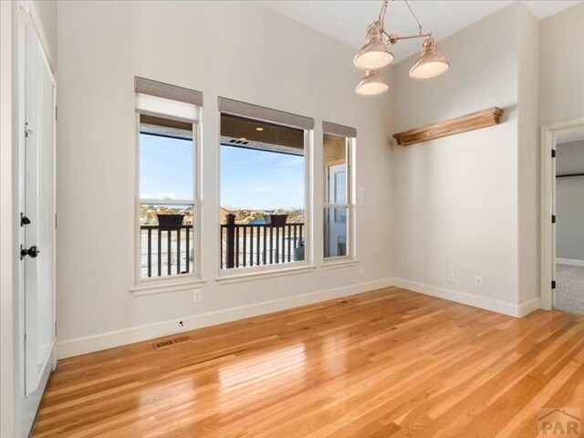 spare room with light wood-style flooring, visible vents, and baseboards