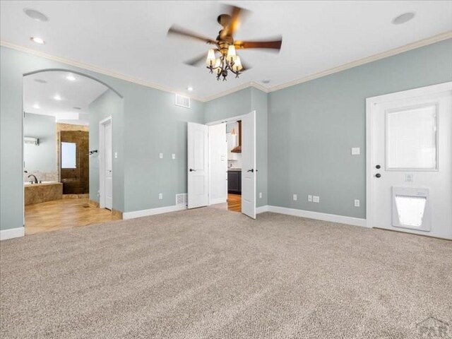 unfurnished bedroom featuring arched walkways, ornamental molding, and light colored carpet