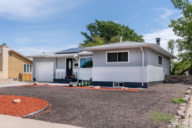 view of front of property featuring a garage and roof mounted solar panels