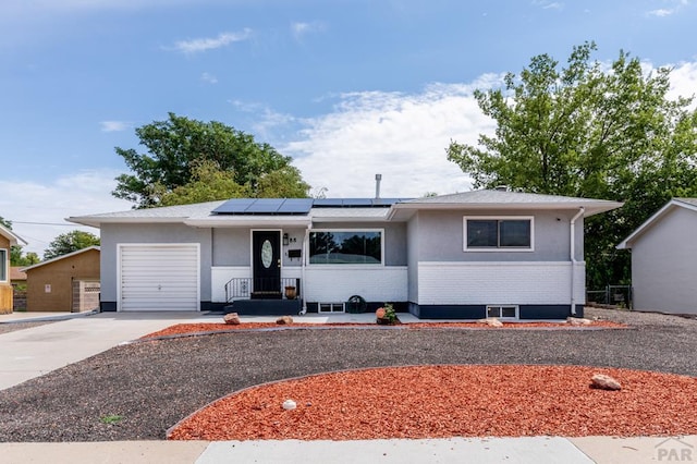 ranch-style home featuring an attached garage, concrete driveway, brick siding, and solar panels