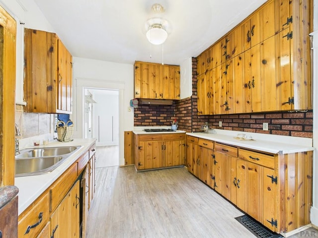 411 Michigan St, Pueblo, CO 81004 - kitchen featuring light wood finished floors, light countertops, backsplash, brown cabinetry, and under cabinet range hood