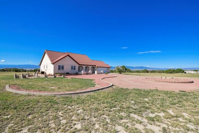 back of property with a yard, stucco siding, a mountain view, driveway, and a tiled roof