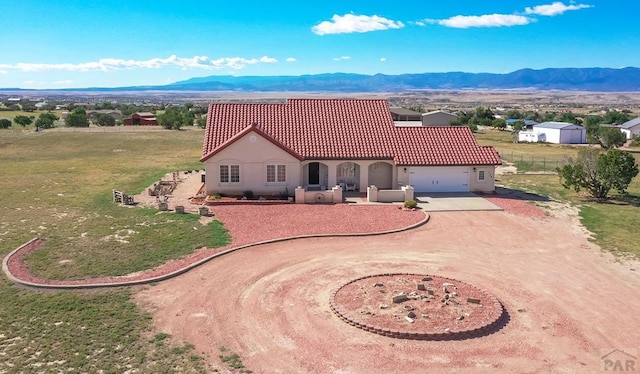 mediterranean / spanish house featuring stucco siding, a tile roof, driveway, and a mountain view