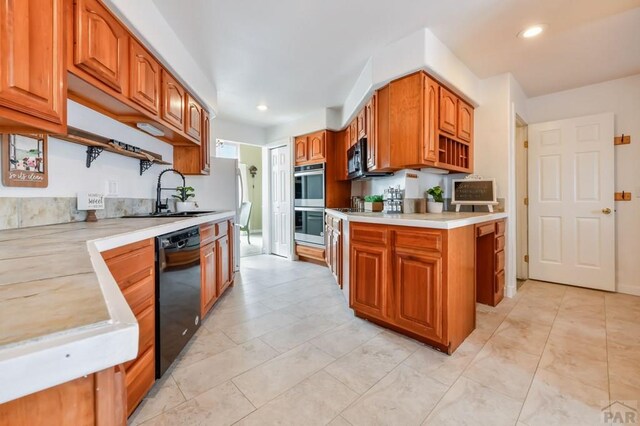 kitchen featuring brown cabinets, light countertops, a sink, and black appliances