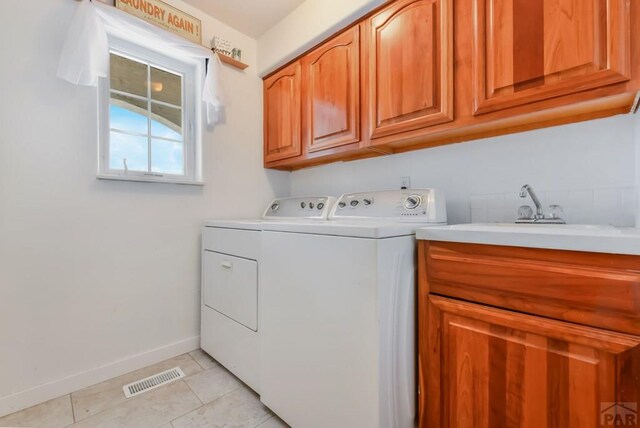 washroom with cabinet space, light tile patterned floors, baseboards, visible vents, and washing machine and clothes dryer