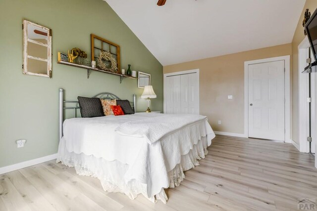 bedroom featuring lofted ceiling, a closet, ceiling fan, light wood-type flooring, and baseboards