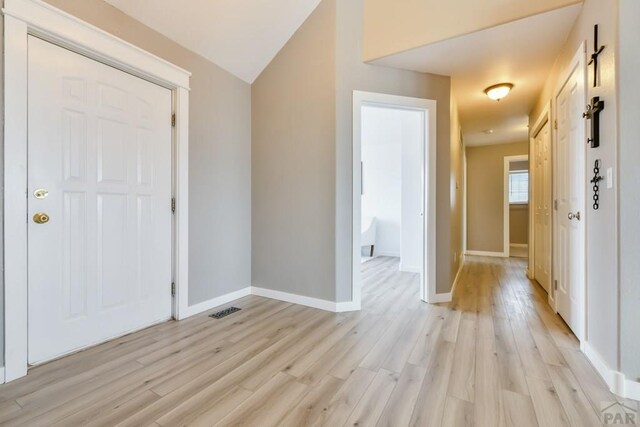 entrance foyer with light wood-style floors, visible vents, vaulted ceiling, and baseboards