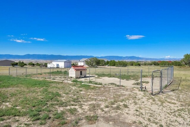 view of yard featuring a rural view, fence, and a mountain view