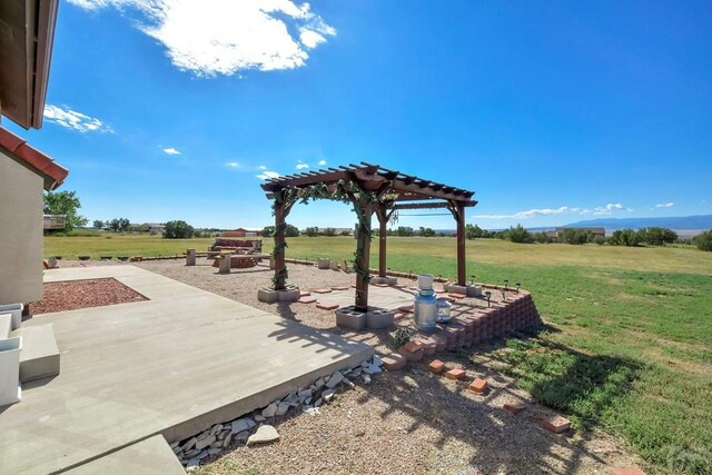 view of yard featuring a rural view, a pergola, and a patio