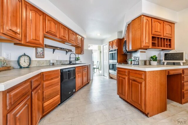 kitchen featuring black dishwasher, light countertops, stainless steel double oven, and a sink