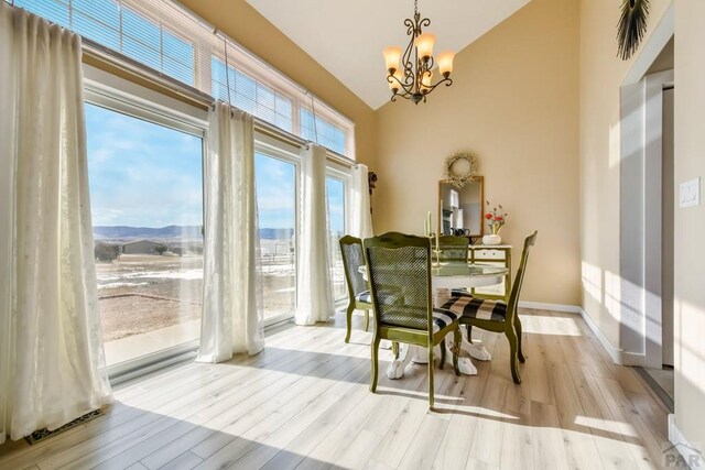 dining area featuring light wood-style floors, baseboards, a mountain view, and a notable chandelier