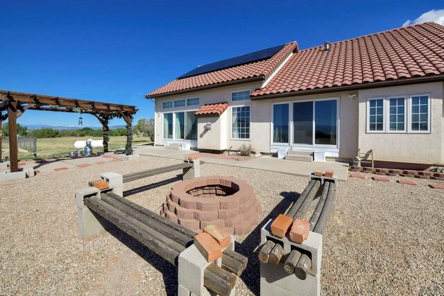 rear view of house with entry steps, an outdoor fire pit, a tiled roof, stucco siding, and a pergola