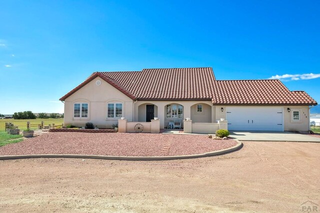 view of front of home with a tile roof, driveway, an attached garage, and stucco siding