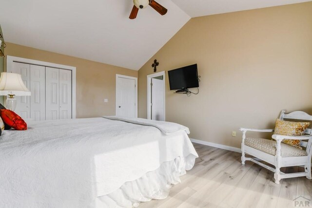 bedroom with light wood finished floors, baseboards, a ceiling fan, lofted ceiling, and a closet