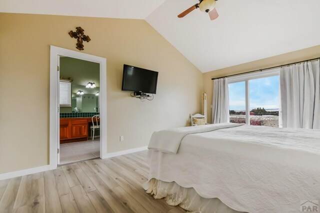 bedroom with light wood finished floors, baseboards, a ceiling fan, lofted ceiling, and ensuite bath