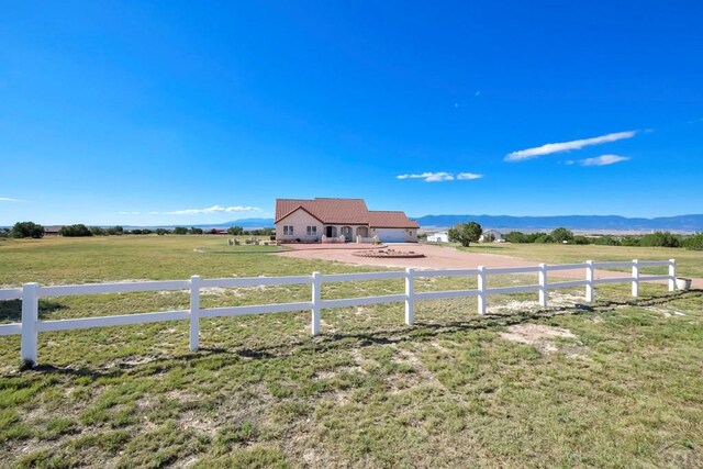 view of yard with fence, a mountain view, and a rural view