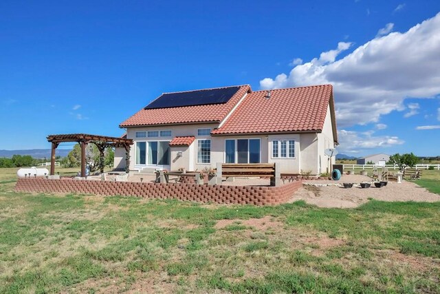 back of house featuring solar panels, a tiled roof, a patio area, a pergola, and stucco siding