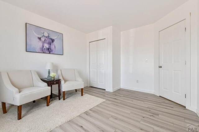 sitting room with baseboards and light wood finished floors