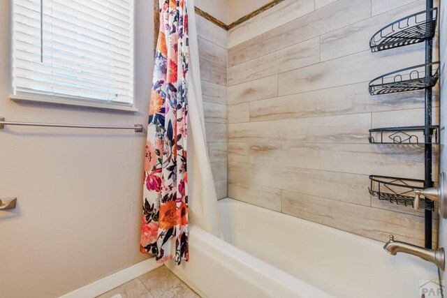 bathroom featuring baseboards, tile patterned flooring, and shower / tub combo with curtain