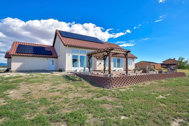 back of house with solar panels, a patio, a tile roof, a pergola, and stucco siding