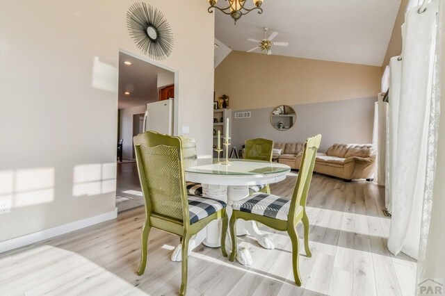 dining area with ceiling fan, visible vents, baseboards, vaulted ceiling, and light wood-style floors