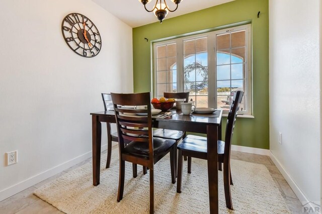 dining room with a chandelier, light tile patterned flooring, and baseboards