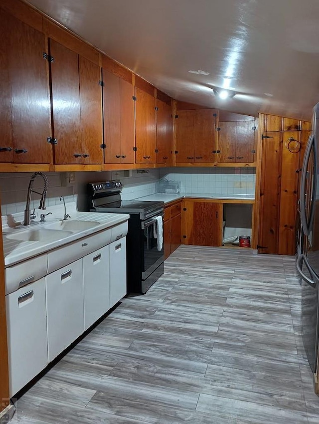 kitchen featuring stainless steel appliances, tasteful backsplash, light countertops, brown cabinetry, and a sink