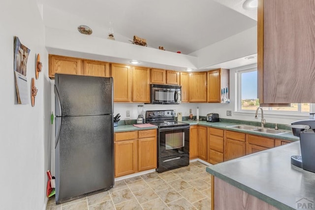 kitchen with stone finish floor, brown cabinets, light countertops, black appliances, and a sink