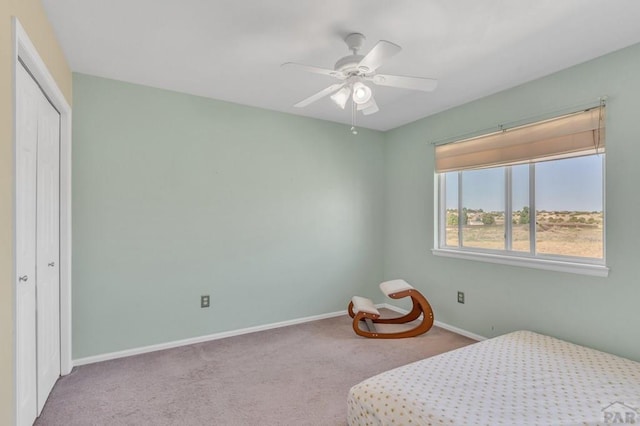 bedroom with ceiling fan, baseboards, a closet, and light colored carpet