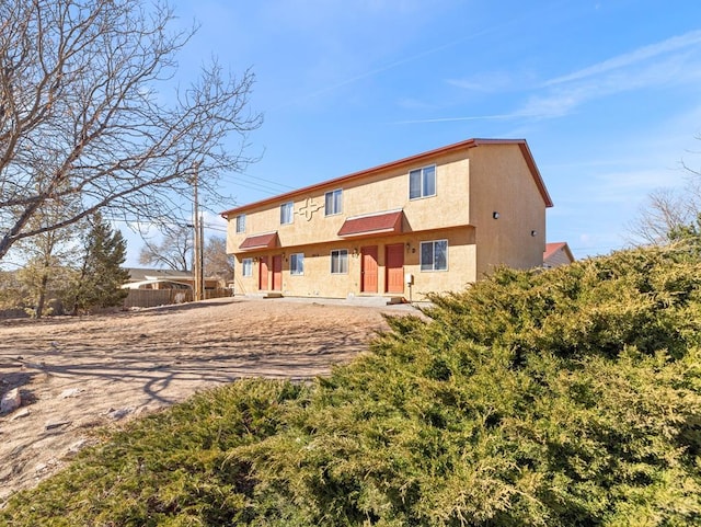 rear view of house featuring fence and stucco siding